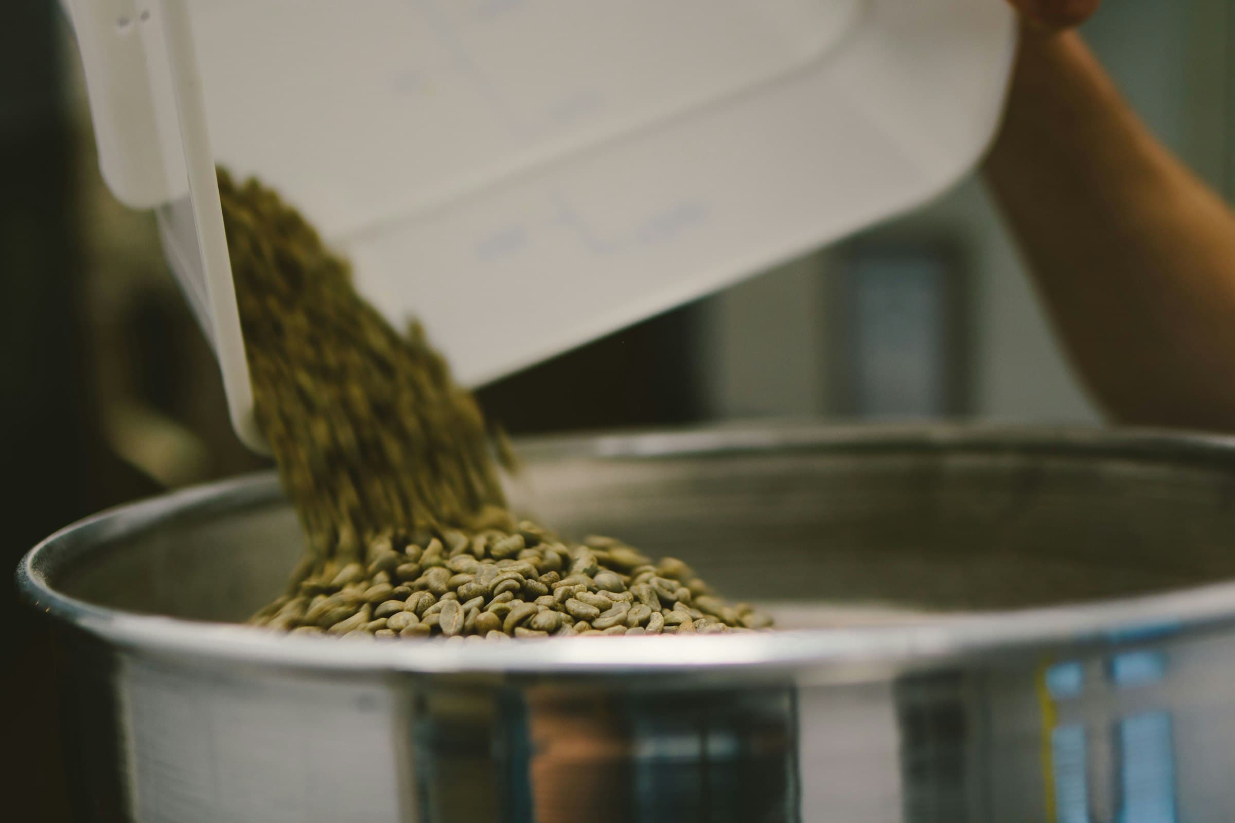 Grano verde cayendo en la tostadora